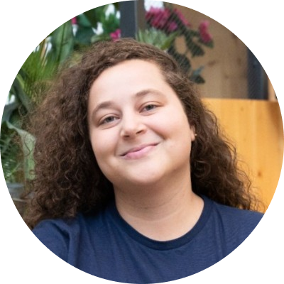 Face image of Isabella Paiva, a white middle-aged woman with curly long brown hair and wearing a dark blue shirt